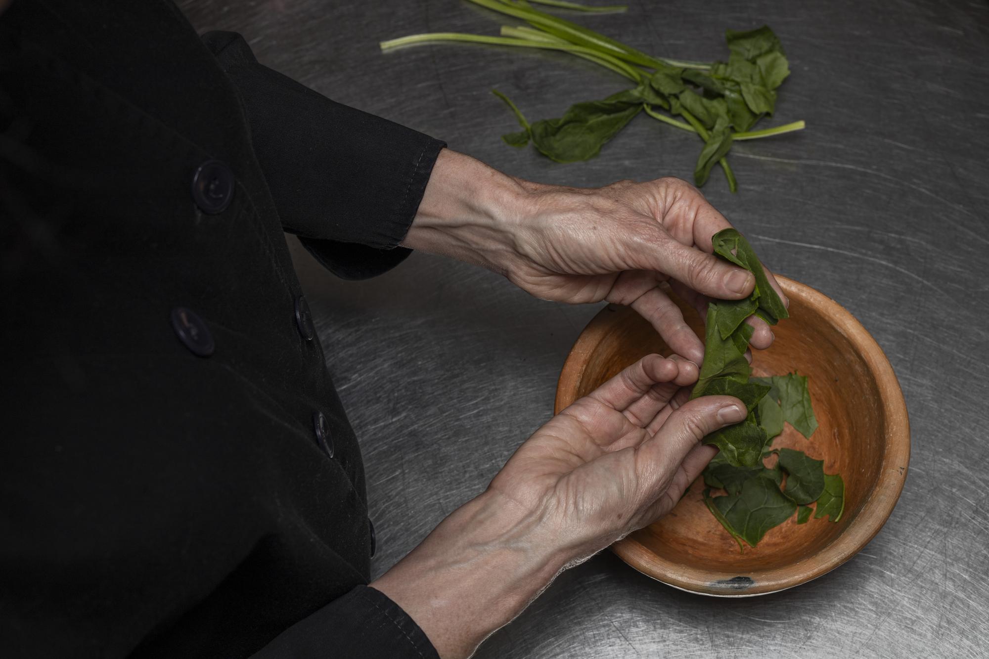 Chef arranging herbs on a wooden board
